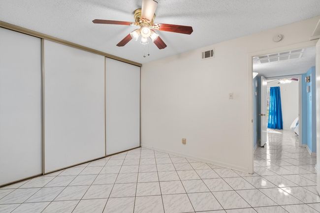 Empty room with a textured ceiling, light tile patterned floors, a ceiling fan, and visible vents | Image 27