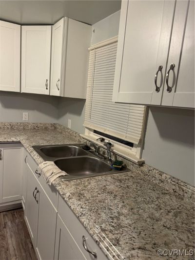 Kitchen featuring light stone counters, sink, white cabinets, and dark hardwood / wood-style floors | Image 2