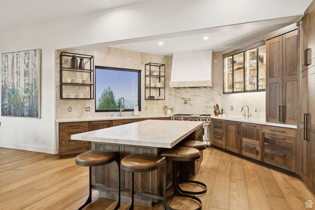 Bar featuring custom range hood, stainless steel stove, light wood-style floors, decorative backsplash, and recessed lighting | Image 4