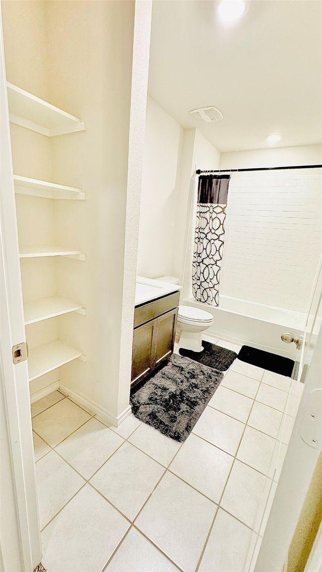 Full bathroom featuring tile patterned flooring, shower / bath combo, vanity, and toilet | Image 18