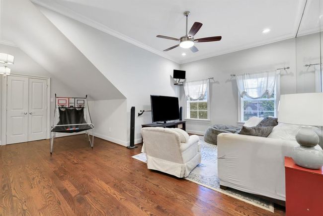 This generously sized secondary bedroom is located at the front of the home and showcases a charming angled ceiling adorned with elegant crown moulding. A modern ceiling fan adds both style and comfort, while the room has been thoughtfully transformed into a dedicated dance space—complete with a mirrored wall and ballet barre. A spacious, oversized walk-in closet provides excellent storage, making this room as functional as it is unique. | Image 30