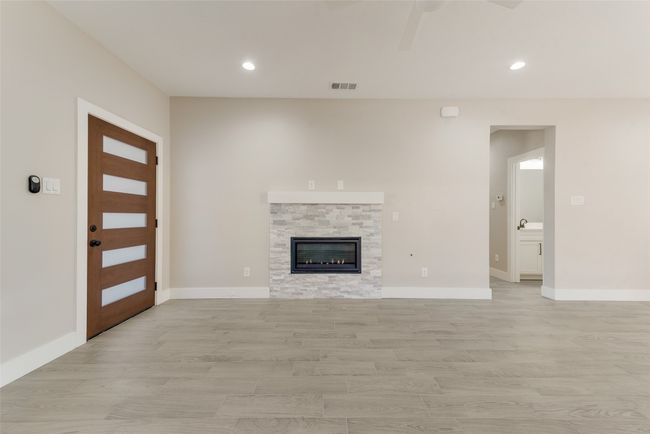 Unfurnished living room with light wood-type flooring, recessed lighting, a ceiling fan, and a stone fireplace | Image 4