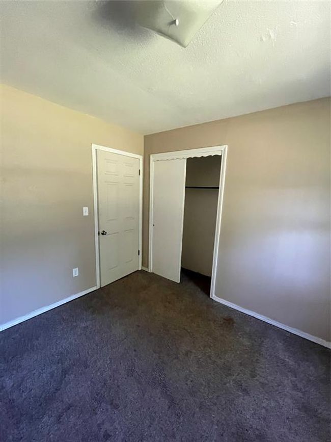 Unfurnished bedroom with dark colored carpet, baseboards, and a closet | Image 15