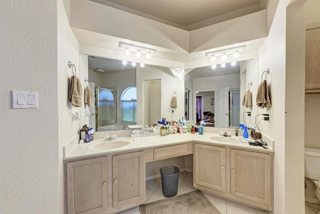 Full bath featuring a textured wall, tile patterned flooring, double vanity, toilet, and a shower | Image 25