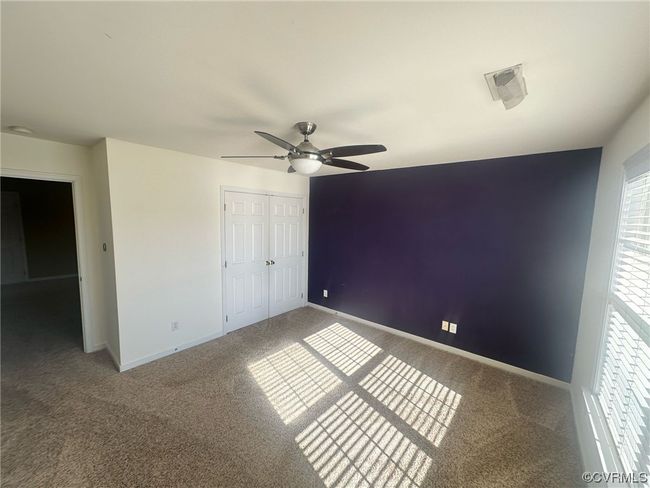 Unfurnished bedroom with ceiling fan, dark carpet, and a closet | Image 8