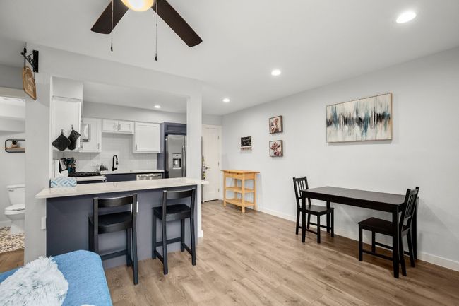 Kitchen with stainless steel refrigerator with ice dispenser, a kitchen breakfast bar, light countertops, a peninsula, and white cabinets | Image 11