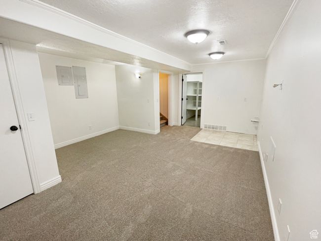 Finished basement with visible vents, ornamental molding, baseboards, carpet flooring, and stairs | Image 24