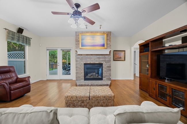 The living room is anchored by a beautiful brick fireplace and it has access to the back patio. | Image 19