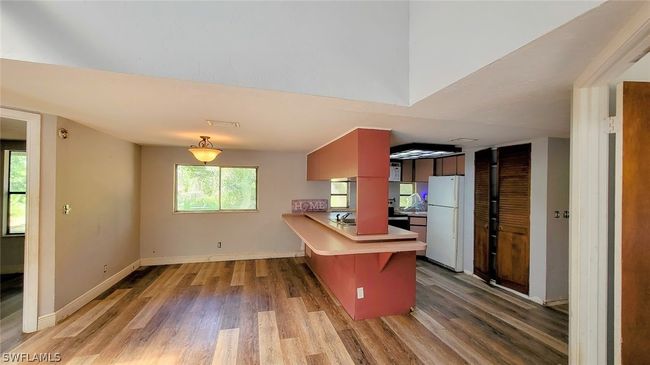 Kitchen featuring white refrigerator, hardwood / wood-style flooring, a breakfast bar area, and a wealth of natural light | Image 7