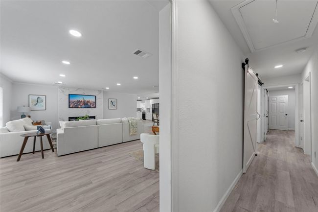 Hallway with recessed lighting, light wood-style floors, attic access, crown molding, and a barn door | Image 10