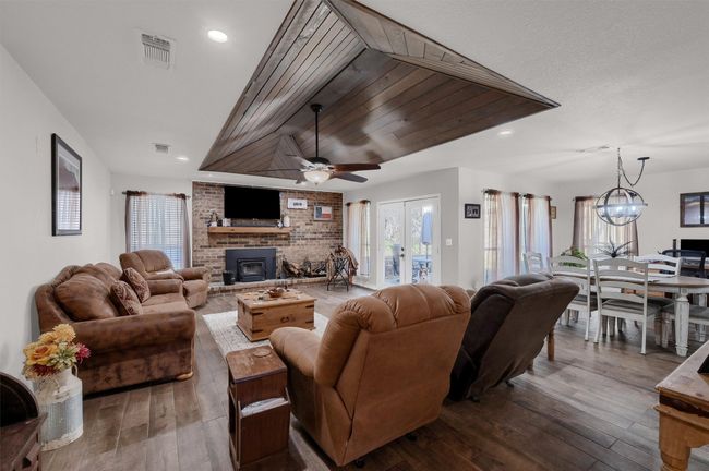 Living room featuring plenty of natural light, wood-type flooring, wooden ceiling, recessed lighting, and ceiling fan | Image 5