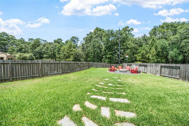 A spacious, private backyard with a meticulously maintained lawn, featuring a stone walkway leading to a cozy, enclosed fire pit area—perfect for relaxation and entertainment. | Image 32
