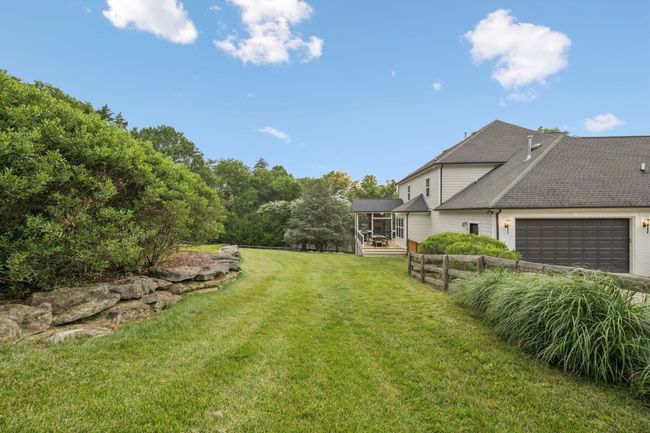 Manicured side lawn with stacked stone accents and fencing—ideal for pets, play, or future pool. | Image 23