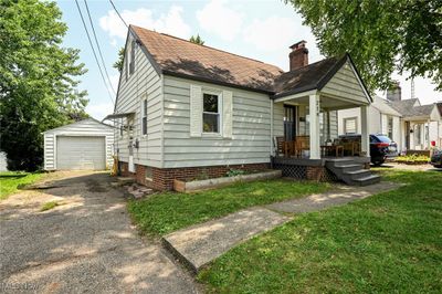 View of front of property with a front yard, an outdoor structure, a garage, and covered porch | Image 2