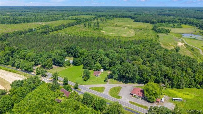 Drone / aerial view of a heavily wooded area and a nearby body of water | Image 5