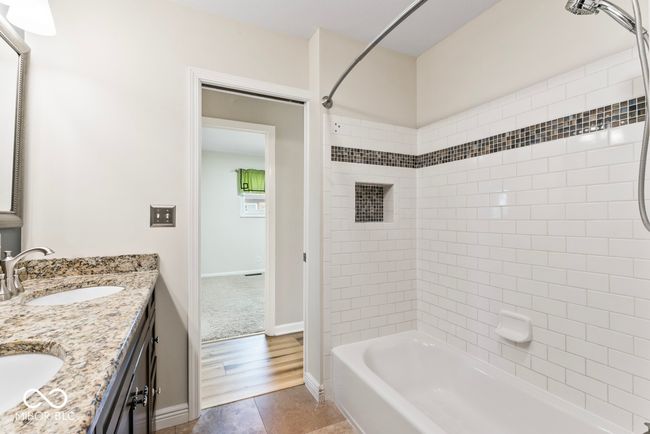 bathroom with bathing tub / shower combination, double vanity, a sink, and baseboards | Image 23