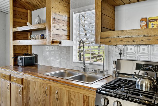 Kitchen with stainless steel range with gas stovetop, a sink, backsplash, and a healthy amount of sunlight | Image 9