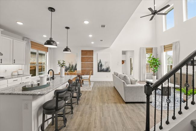Kitchen featuring ceiling fan, white cabinets, recessed lighting, a kitchen island with sink, and light stone counters | Image 12