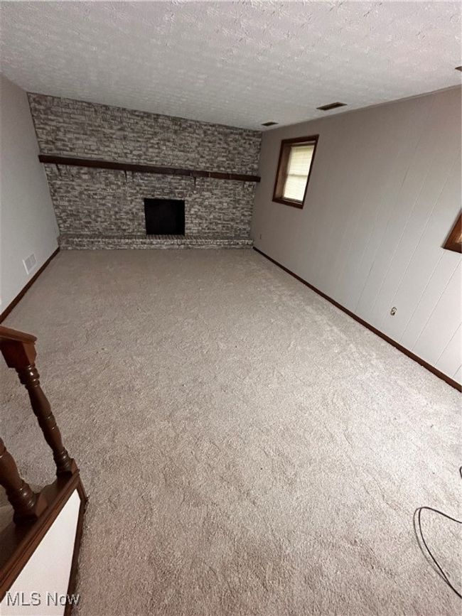 Unfurnished living room with a textured ceiling, visible vents, and carpet floors | Image 6
