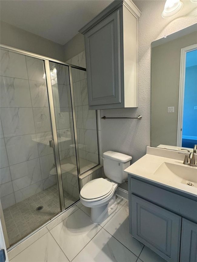 Full bathroom with marble look tile flooring, vanity, and a shower stall | Image 30