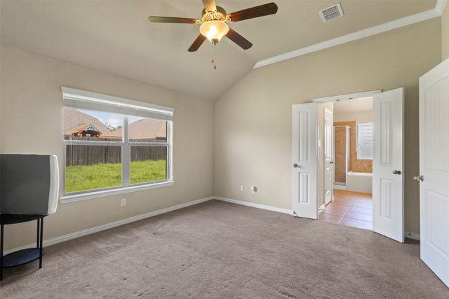 Unfurnished bedroom with vaulted ceiling, carpet, ensuite bathroom, and a ceiling fan | Image 21