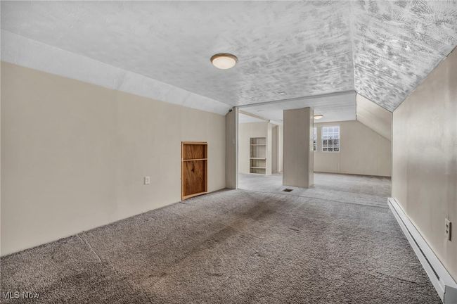 Additional living space featuring a baseboard radiator, carpet floors, and lofted ceiling | Image 43