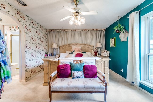 Bedroom featuring light colored carpet, arched walkways, ensuite bathroom, and a ceiling fan | Image 13