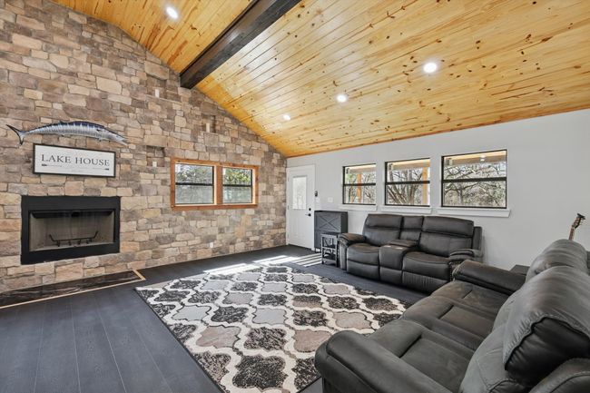 Living area with a fireplace, high vaulted ceiling, wooden ceiling, beamed ceiling, and hardwood / wood-style flooring | Image 5