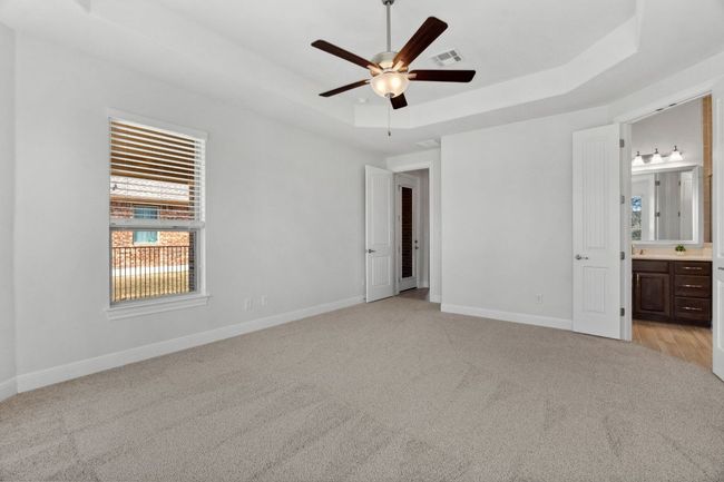 Unfurnished bedroom featuring visible vents, baseboards, a tray ceiling, light colored carpet, and connected bathroom | Image 21