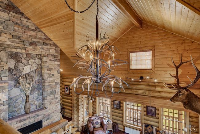 Detailed view of a wooden ceiling with exposed beams, log walls, a chandelier, and radiator heating unit | Image 34