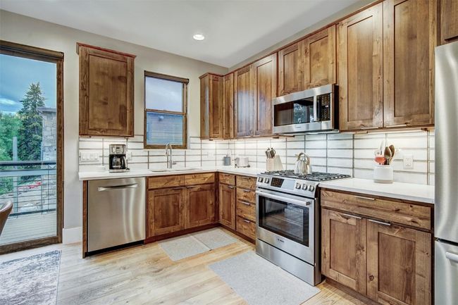 Kitchen with a sink, light wood-style flooring, stainless steel appliances, and decorative backsplash | Image 5