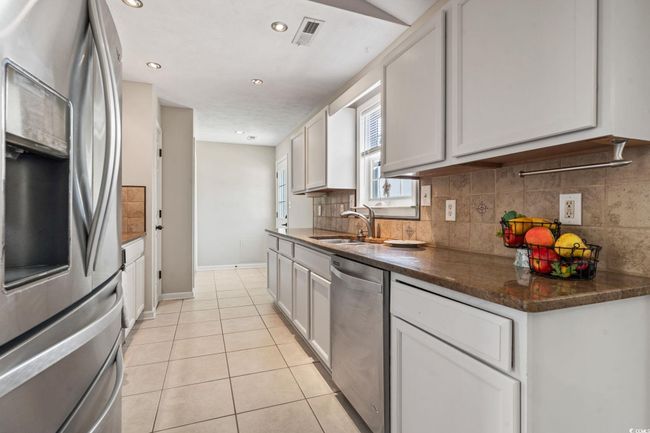 Kitchen featuring appliances with stainless steel finishes, backsplash, light tile patterned flooring, white cabinets, and recessed lighting | Image 13