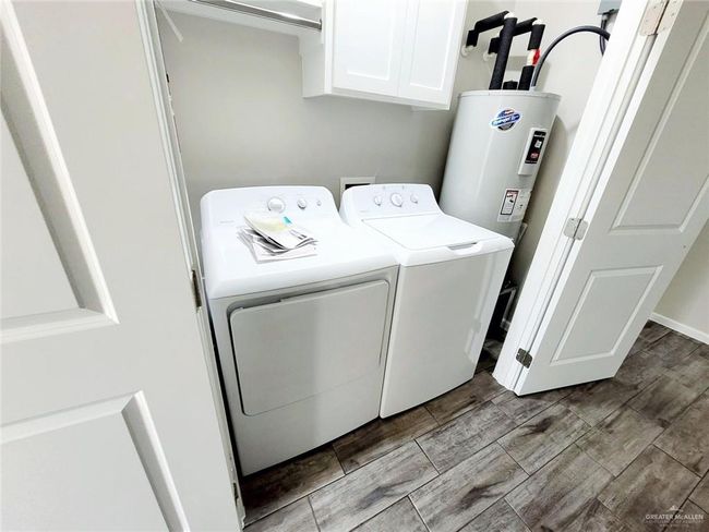 Laundry room featuring cabinet space, washing machine and clothes dryer, water heater, and wood finish floors | Image 13