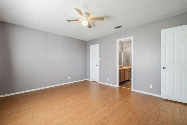 Unfurnished bedroom with light wood-style flooring, a textured ceiling, ensuite bath, and ceiling fan | Image 21