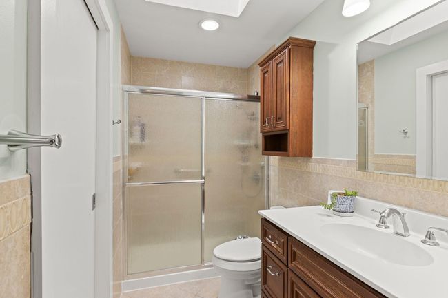 Full bath with tile patterned flooring, vanity, tile walls, toilet, and a glass enclosed shower | Image 16