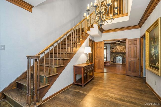 The wooden stairs lead to the top level and the stairs to the lower level are in the hallway on the main bedroom wing. Beautiful hardwood. | Image 15
