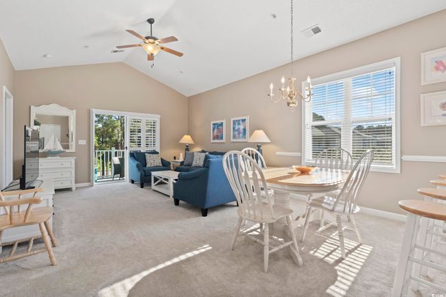 Dining area with light colored carpet, ceiling fan, vaulted ceiling, a chandelier, and baseboards | Image 10