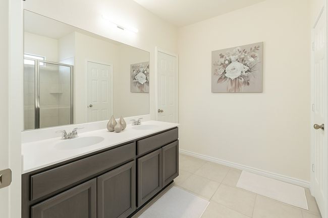 Full bath with a shower stall, baseboards, double vanity, and a sink | Image 11