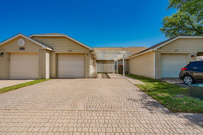 Ranch-style house with a pergola, decorative driveway, and brick siding | Image 9