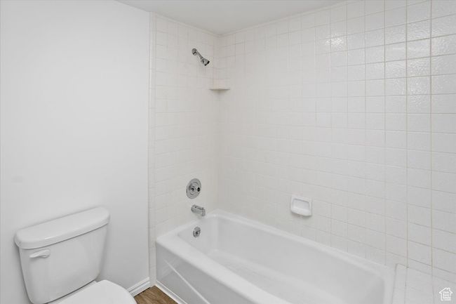 Bathroom featuring shower / washtub combination, wood finished floors, toilet, and baseboards | Image 33