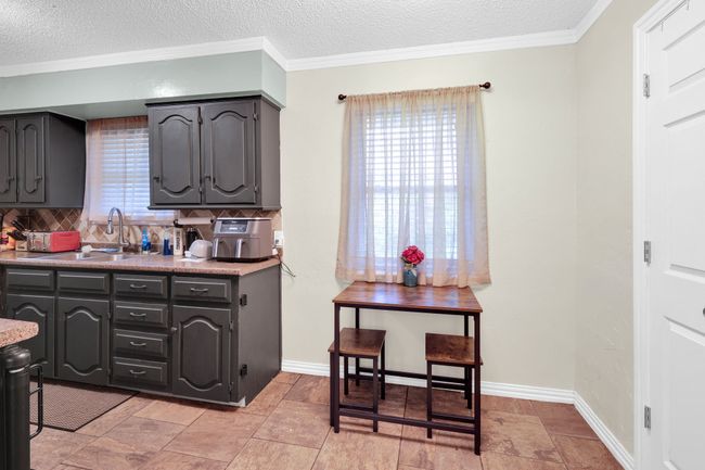 Kitchen featuring tasteful backsplash, ornamental molding, a textured ceiling, and light countertops | Image 14