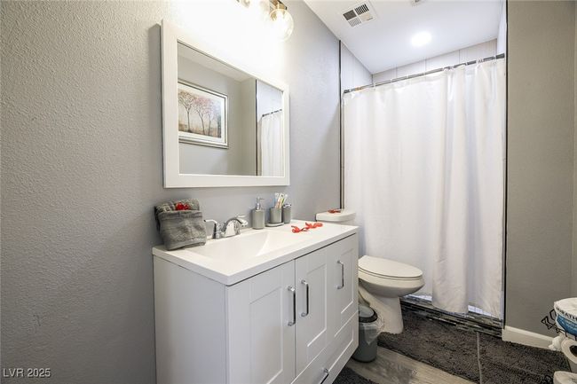 Full bathroom with toilet, vanity, a textured wall, and wood finished floors | Image 34