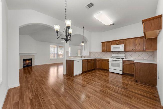 Kitchen featuring a sink, dark wood finished floors, white appliances, brown cabinetry, and lofted ceiling | Image 8