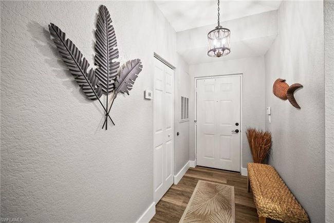Doorway to outside featuring an inviting chandelier, a textured wall, and wood finished floors | Image 5