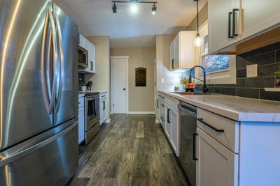 Kitchen features S.S. appliances, white shaker cabinets, slate backsplash, and a pantry with French doors. | Image 3