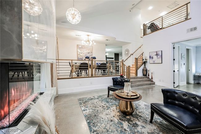 Living area featuring visible vents, baseboards, a chandelier, a towering ceiling, and finished concrete floors | Image 7