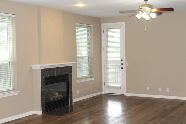 Unfurnished living room with ceiling fan, wood finished floors, a fireplace, and plenty of natural light | Image 6