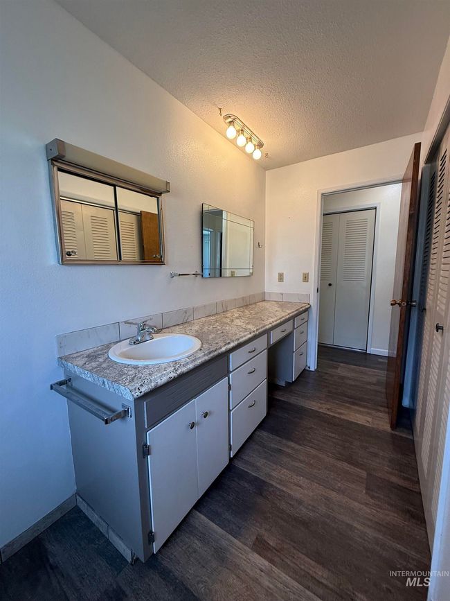 Bathroom featuring wood finished floors, vanity, a textured ceiling, and a closet | Image 21