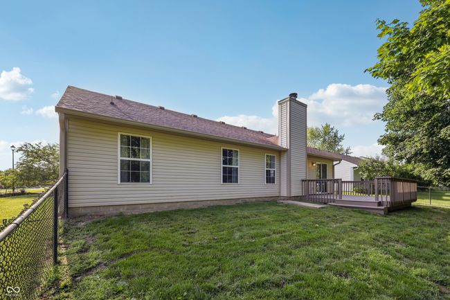 back of house featuring a fenced backyard, a deck, a chimney, and a shingled roof | Image 33