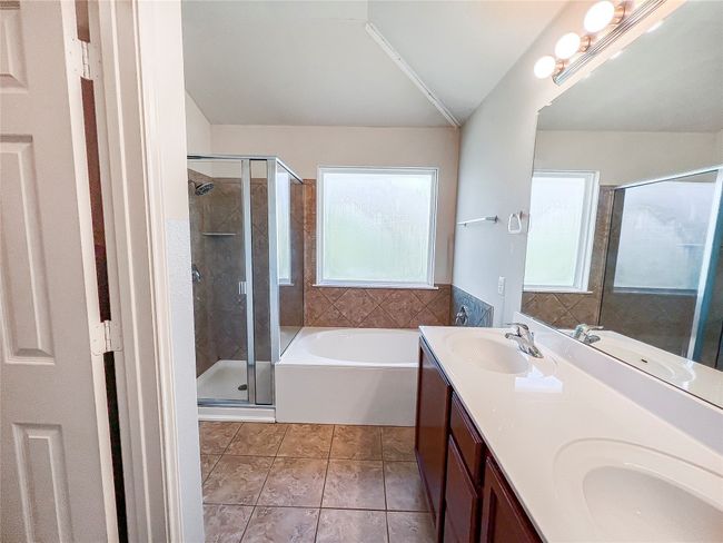 Bathroom with a garden tub, a shower stall, double vanity, vaulted ceiling, and tile patterned flooring | Image 24